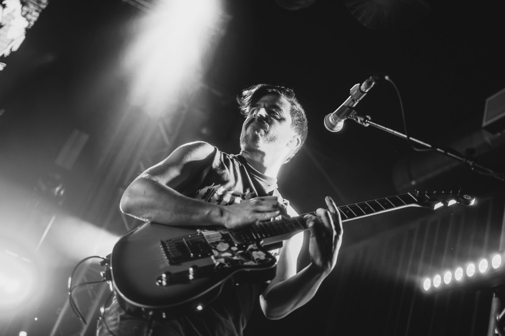 A musician playing an electric guitar passionately on stage, with dramatic lighting creating a dynamic atmosphere.