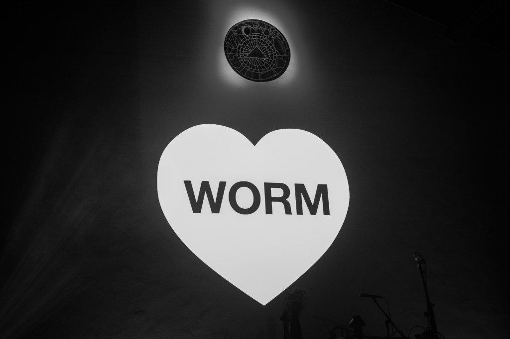 A heart-shaped projection with the word 'WORM' in bold letters against a dark background.