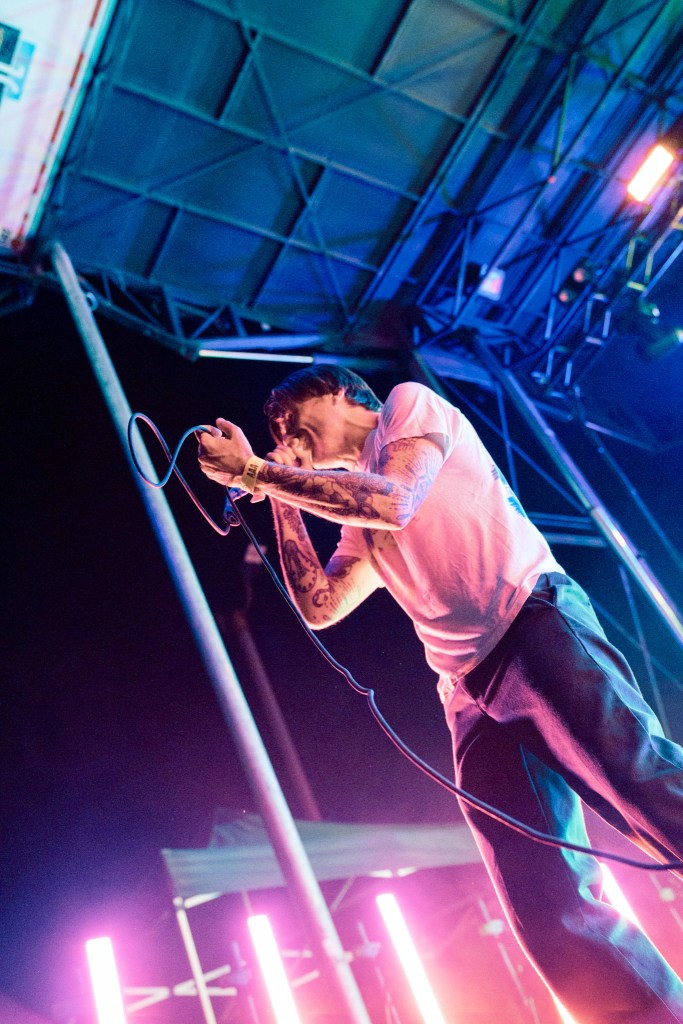 A singer passionately performing on stage with a microphone, surrounded by colorful lighting effects.